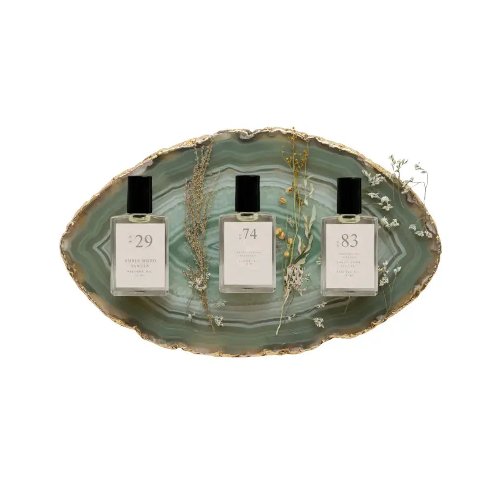 Three perfume bottles with labels on a decorative stone platter