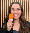 Woman holding a bottle of Think Sun Serum sunscreen with a wooden panel background