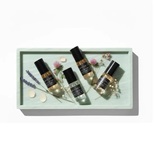 Four small bottles with black labels on a light green tray with flowers and leaves.