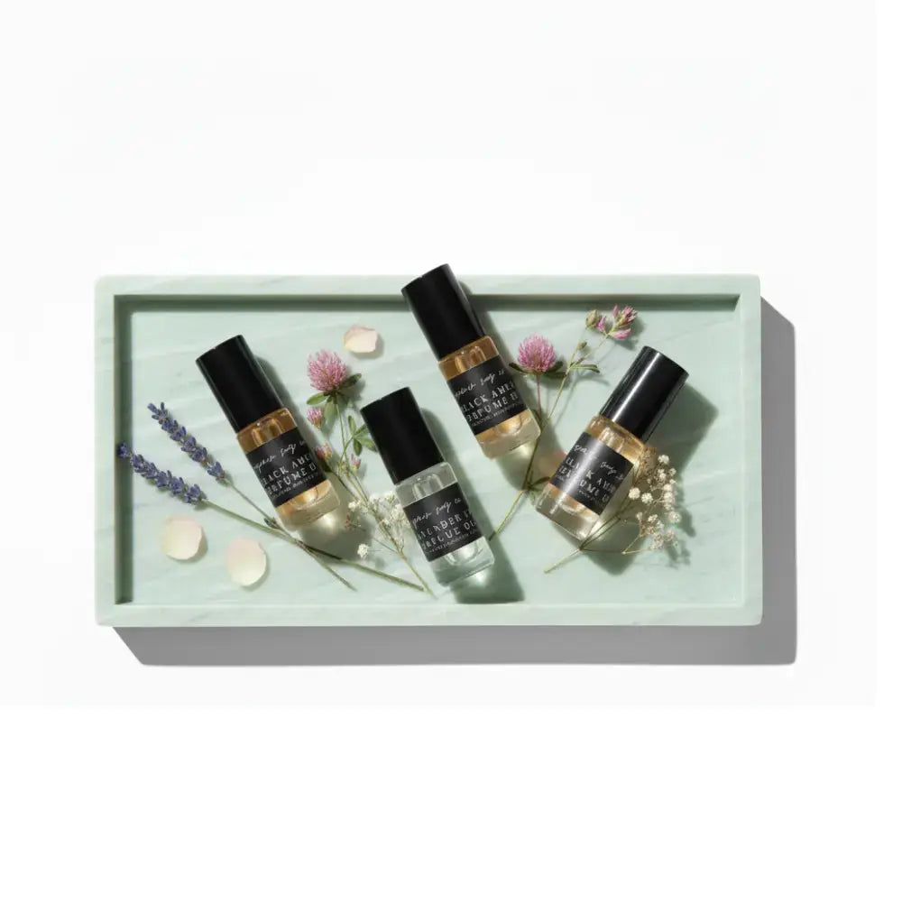 Four small bottles with black labels on a light green tray with flowers and leaves.