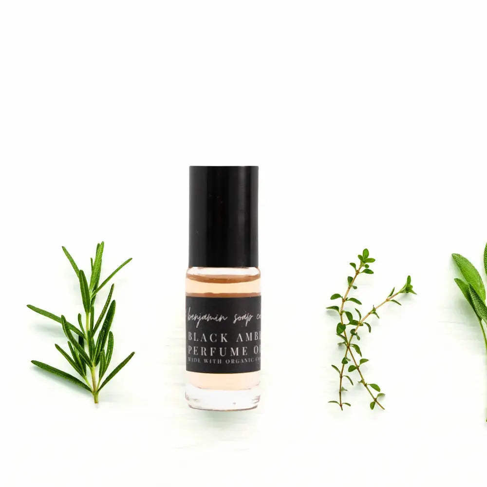 Perfume bottle with green leaves on a white background