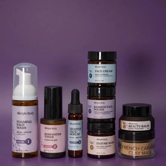 A Mini Starter Skincare kit for mature skin including a Foaming Face Wash, Rosewater Toner, Nightly Face Serum, Face Cream, Bamboo Face Polish, Enzyme Mask, Beauty Balm, and Clay Mask on a purple background.