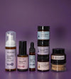 A Mini Starter Skincare kit for mature skin including a Foaming Face Wash, Rosewater Toner, Nightly Face Serum, Face Cream, Bamboo Face Polish, Enzyme Mask, Beauty Balm, and Clay Mask on a purple background.