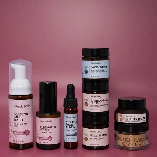A Mini Starter Skincare kit for normal to dry skin including a Foaming Face Wash, Rosewater Toner, Nightly Face Serum, Face Cream, Bamboo Face Polish, Enzyme Mask, Beauty Balm, and Clay Mask on a rosey pink background.