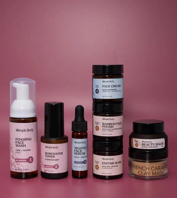 A Mini Starter Skincare kit for normal to dry skin including a Foaming Face Wash, Rosewater Toner, Nightly Face Serum, Face Cream, Bamboo Face Polish, Enzyme Mask, Beauty Balm, and Clay Mask on a rosey pink background.