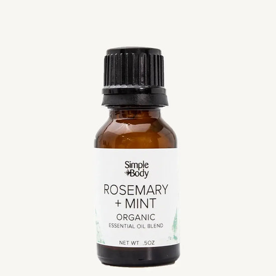 Brown glass bottle of Simple Body Rosemary + Mint organic essential oil blend on a white background