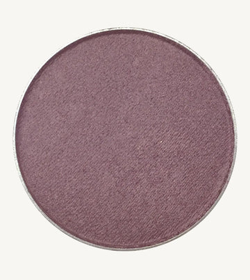 A photo of Pure Anada's Pressed Eye Color in Grape which is a deep purple color on a tan background.