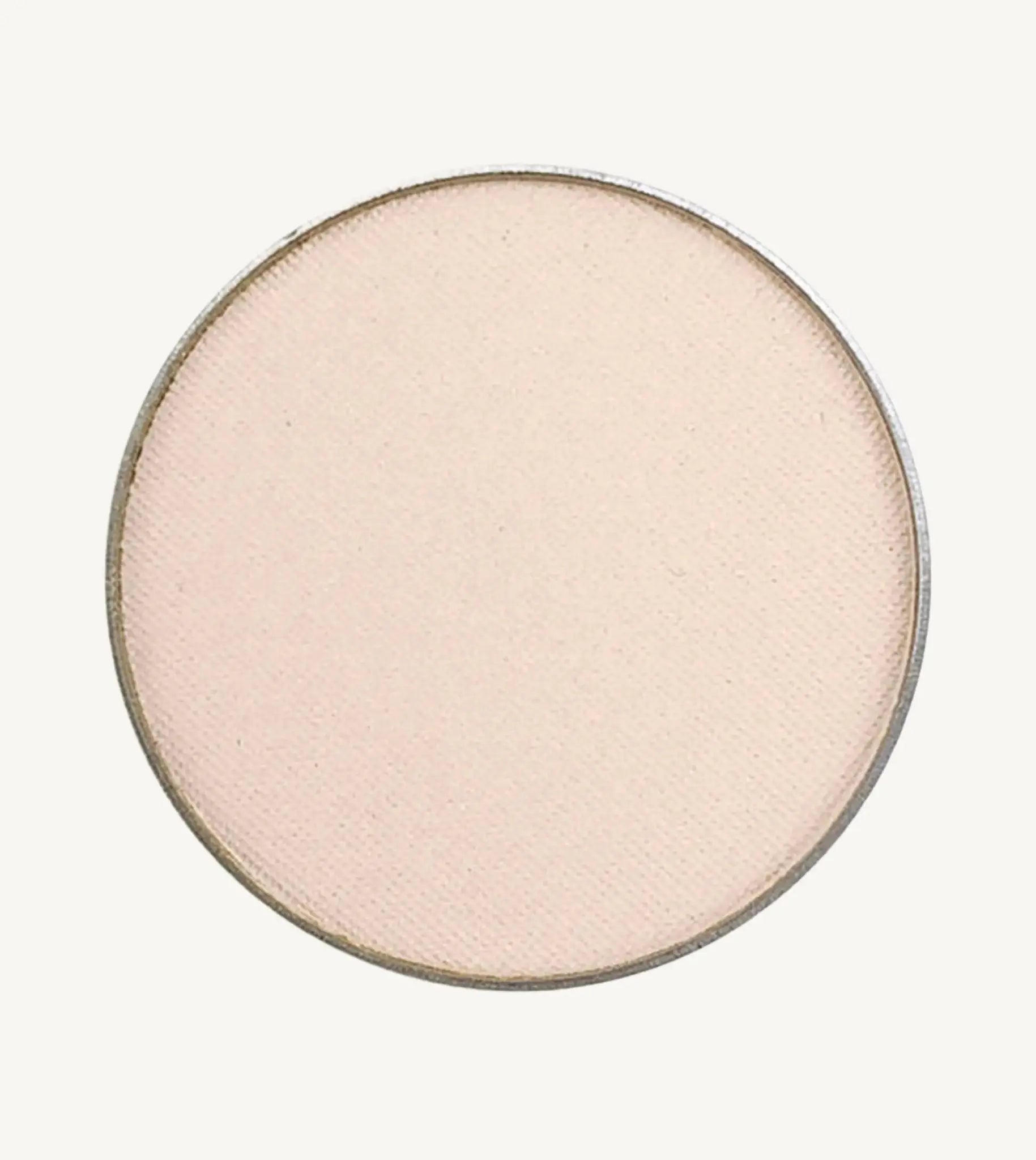 A photo of Pure Anada's Pressed Eye Color in Ivory Tower which is an off-white color with a pinkish hue on a tan background.