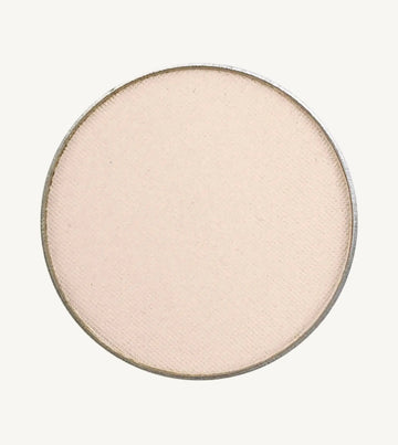 A photo of Pure Anada's Pressed Eye Color in Ivory Tower which is an off-white color with a pinkish hue on a tan background.