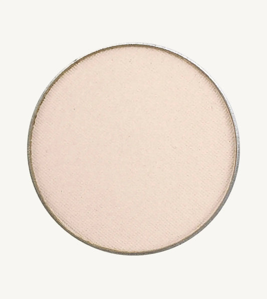 A photo of Pure Anada's Pressed Eye Color in Ivory Tower which is an off-white color with a pinkish hue on a tan background.