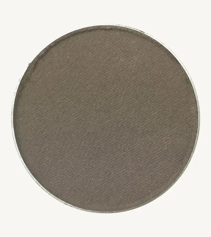 A photo of Pure Anada's Pressed Eye Color in Smoke (Matte) which is a warm brown / gray color on a tan background.