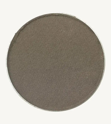 A photo of Pure Anada's Pressed Eye Color in Smoke (Matte) which is a warm brown / gray color on a tan background.