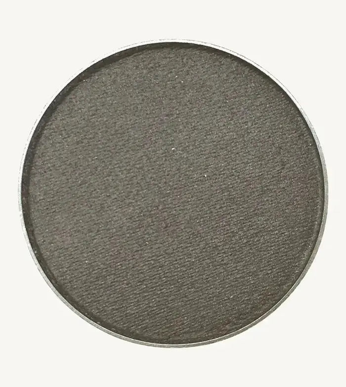 A photo of Pure Anada's Pressed Eye Color in Pewter which is a dark gray with a hint of shimmer on a tan background.