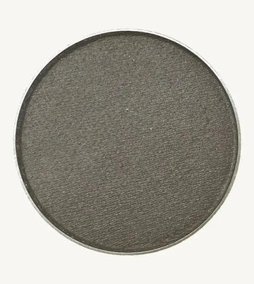 A photo of Pure Anada's Pressed Eye Color in Pewter which is a dark gray with a hint of shimmer on a tan background.