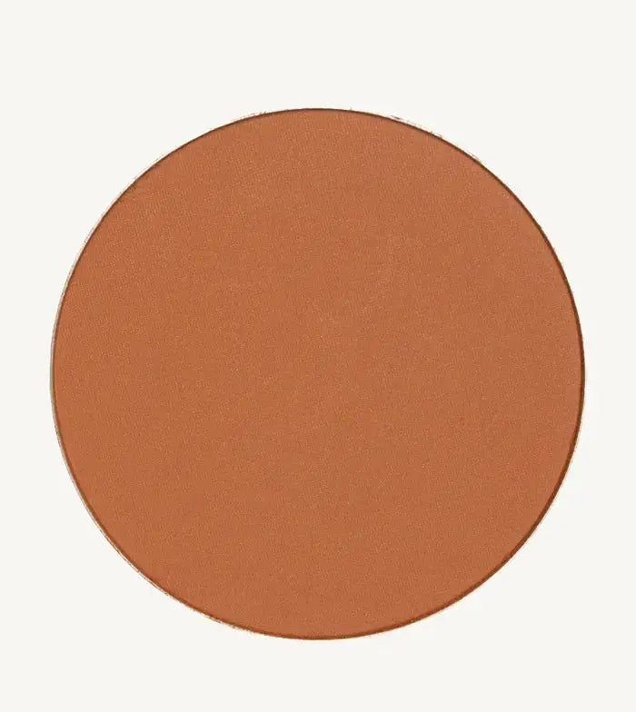 A photo of Pure Anada's Global Pressed Foundation powder which is a cinnamon brown orange color on a tan background.