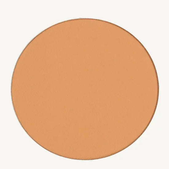 A photo of Pure Anada's Pressed Foundation Powder in Medium which is a warm peach honey color on a tan background.