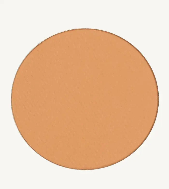A photo of Pure Anada's Pressed Foundation Powder in Medium which is a warm peach honey color on a tan background.