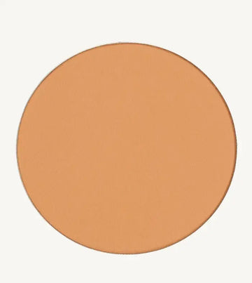 A photo of Pure Anada's Pressed Foundation Powder in Medium which is a warm peach honey color on a tan background.