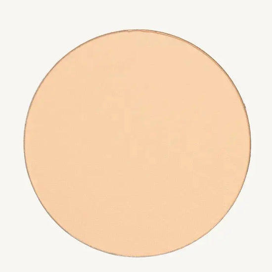 A photo of Pure Anada's Pressed Sheer Foundation Powder in Porcelain which is a light beige with a hint of peach color on a tan background.