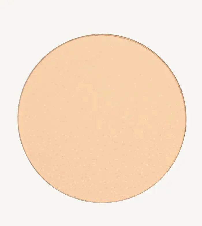 A photo of Pure Anada's Pressed Sheer Foundation Powder in Porcelain which is a light beige with a hint of peach color on a tan background.