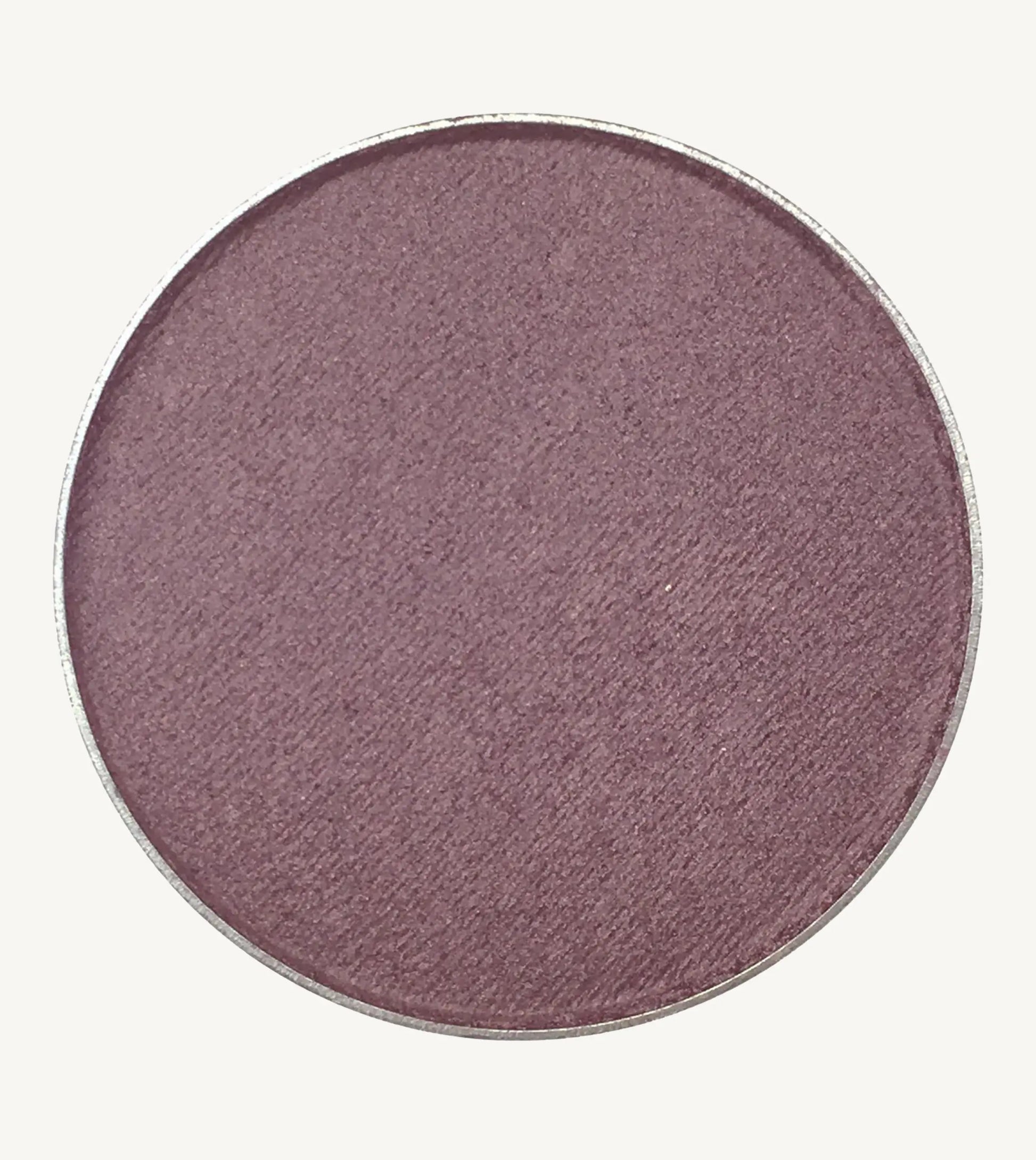 A photo of Pure Anada's Pressed Eye Color in Grape which is a deep purple color on a tan background.