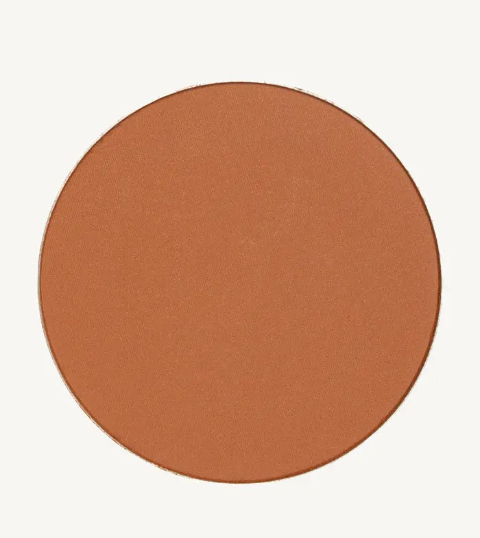 A photo of Pure Anada's Global Pressed Foundation powder which is a cinnamon brown orange color on a tan background.