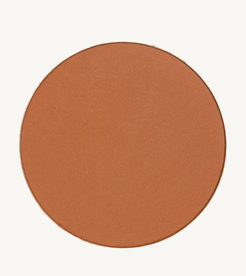 A photo of Pure Anada's Global Pressed Foundation powder which is a cinnamon brown orange color on a tan background.