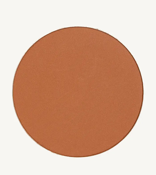 A photo of Pure Anada's Global Pressed Foundation powder which is a cinnamon brown orange color on a tan background.