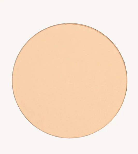 A photo of Pure Anada's Pressed Sheer Foundation Powder in Porcelain which is a light beige with a hint of peach color on a tan background.
