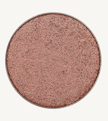 A photo of Pure Anada's Pressed Eye Color in Reverie which is a shimmering rose pink color on a tan background.