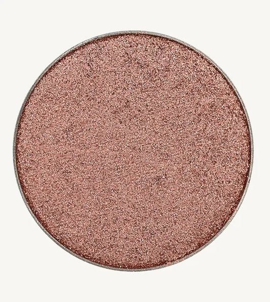 A photo of Pure Anada's Pressed Eye Color in Reverie which is a shimmering rose pink color on a tan background.