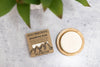Rock Creek Soaps shampoo bar with packaging on a textured surface with green leaves.