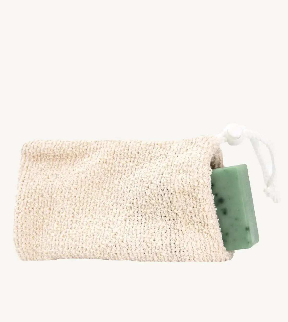 A natural cotton soap saver bag with a green soap bar inside, tied with a white string.