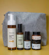 A Starter Skincare Kit for combination skin with a foaming face wash, Clean Sweep Toner, Nightly Face Serum, Beauty Balm, Face Cream, and a gray cosmetic bag on a yellow background.