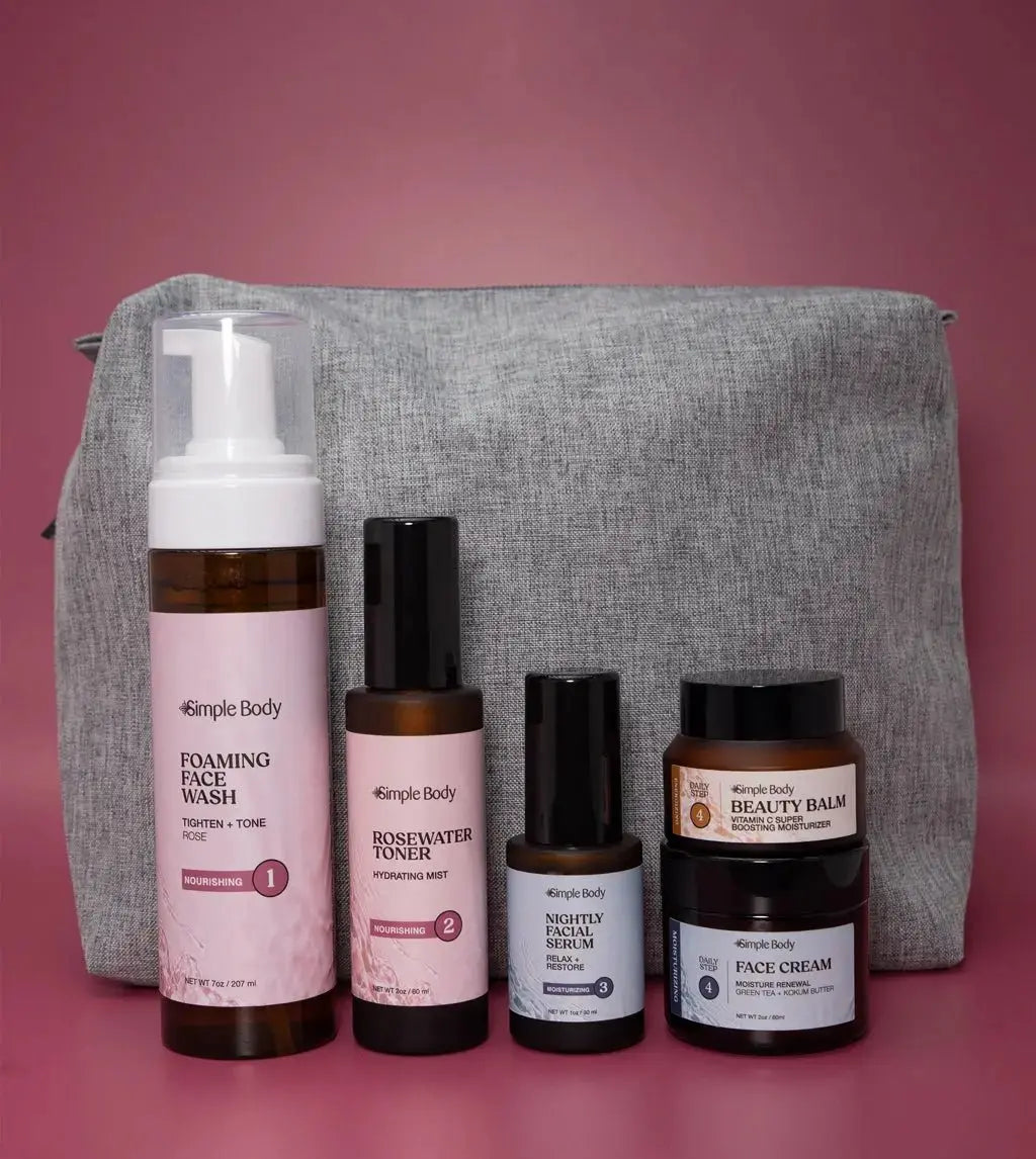 A Starter Skincare Kit for Normal to Dry skin with a foaming face wash, Rosewater Toner, Nightly Face Serum, Beauty Balm, Face Cream, and a gray cosmetic bag on a rosy pink background.