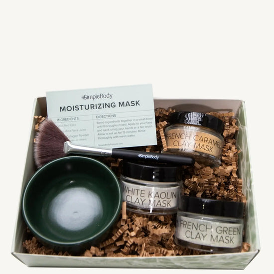A photo of a Simple Body triple clay mask gift set including French Caramel Clay, White Kaolin Clay and French Green Clay with a dark green bowl, fan brush and recipe card.