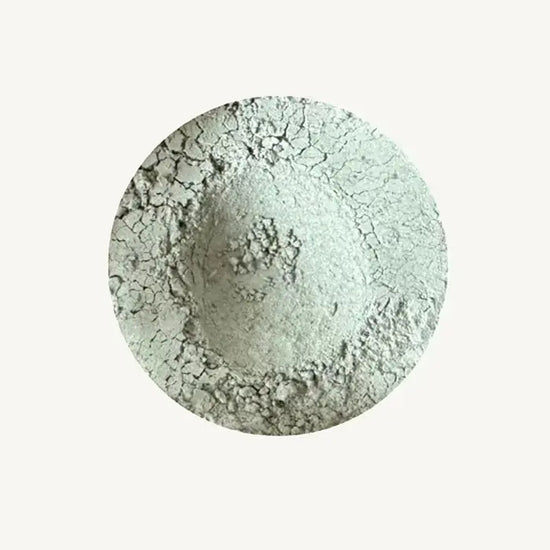 A photo of Pure Anada's Velvet Loose Matte Eyeshadow in Gray Flannel which is a light gray green color on a tan background.