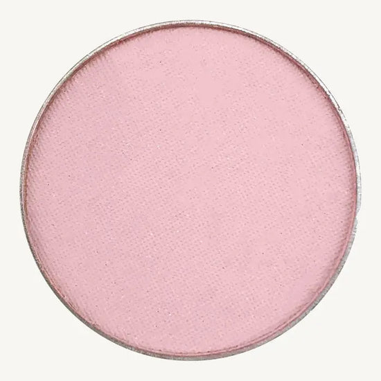 A photo of Pure Anada's Pressed Eye Color Water Lily which is a ballet pink on a tan background.