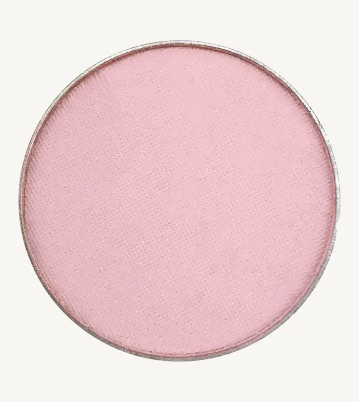 A photo of Pure Anada's Pressed Eye Color Water Lily which is a ballet pink on a tan background.