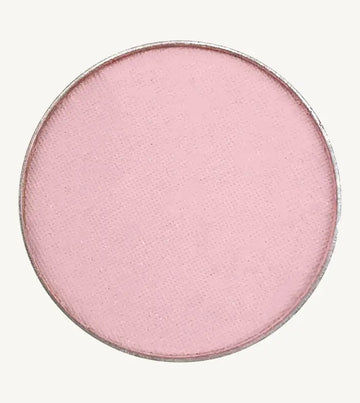 A photo of Pure Anada's Pressed Eye Color Water Lily which is a ballet pink on a tan background.