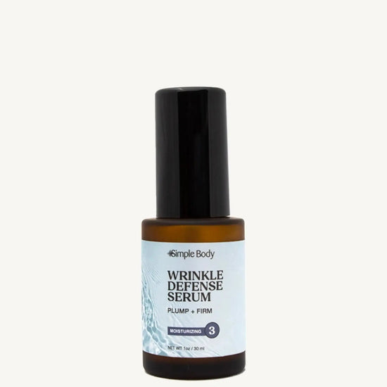 A bottle of Simple Body Wrinkle Defense Serum with a black cap and white label, containing a lightweight facial serum designed to smooth and plump the skin.