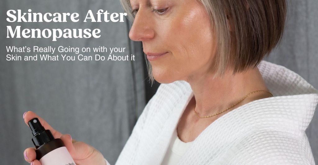 A mature woman looks down at a skincare product. She has beautiful, glowing skin.